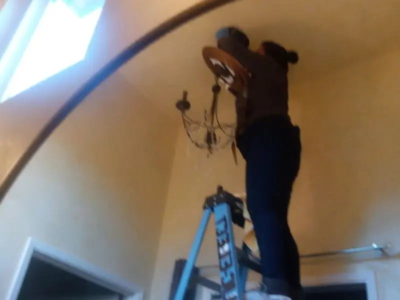Electrician installing a chandelier in a Sterling residence